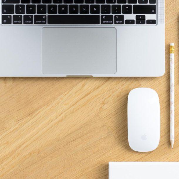 Laptop, Maus, Handy auf einem Holztisch symbolisieren den Blogbeitrag: Marke erfolgreich aufbauen in 5 Schritten