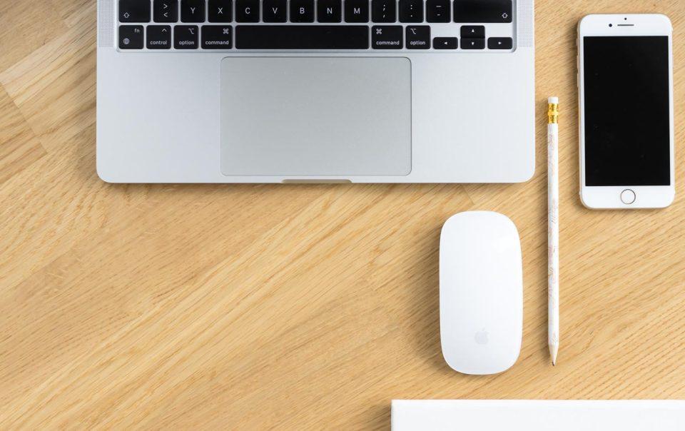 Laptop, Maus, Handy auf einem Holztisch symbolisieren den Blogbeitrag: Marke erfolgreich aufbauen in 5 Schritten