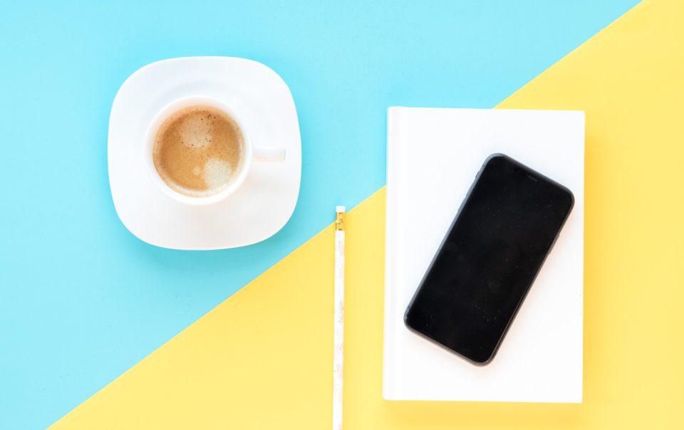 Bild mit Tasse, Bleistift, Handy und Notizblock - ein Arbeitsplatz zum Thema Content Marketing