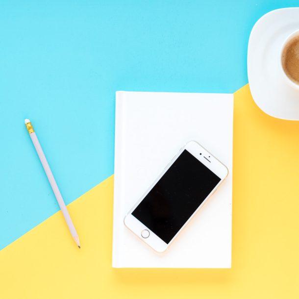 Bunte Tischplatte mit Kaffeetasse, Block und Stift, Handy - alles liegt bereit für einen Workshop