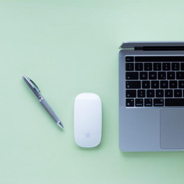 Laptop, Maus und Stift zum Schreiben von Willkommens-E-Mails