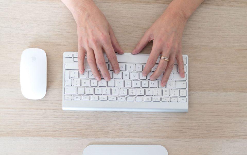 Sicht von oben auf eine Tastatur, Maus und zwei Hände - es werden SEO Tipps geschrieben