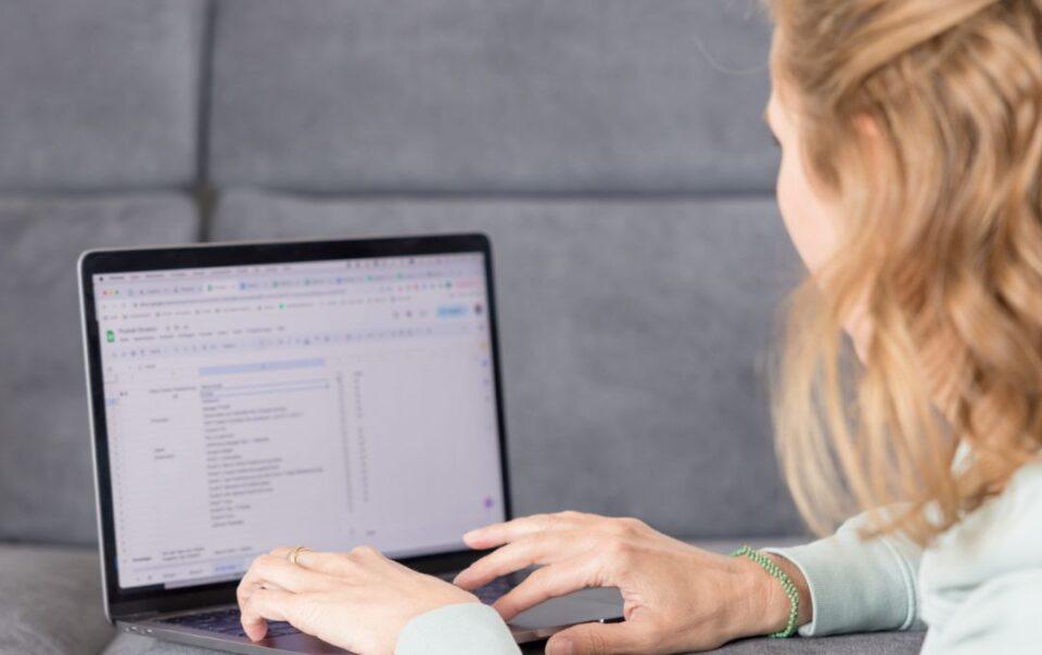 Christina arbeitet am laptop am Boden sitzend