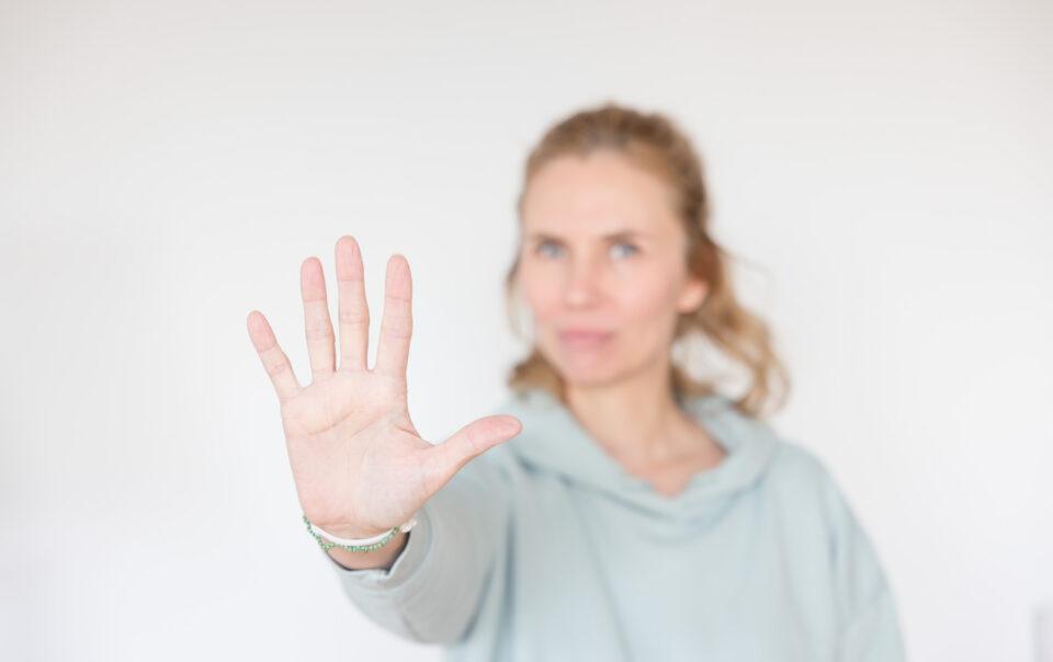 Christina streckt Hand aus und signalisiert damit Stopp. Beitragsbild zum Artikel: Gedanken die deinen Erfolg blockieren